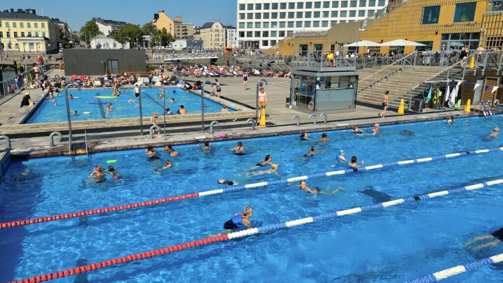 People swimming in outdoor swimming pools on a sunny summer day.