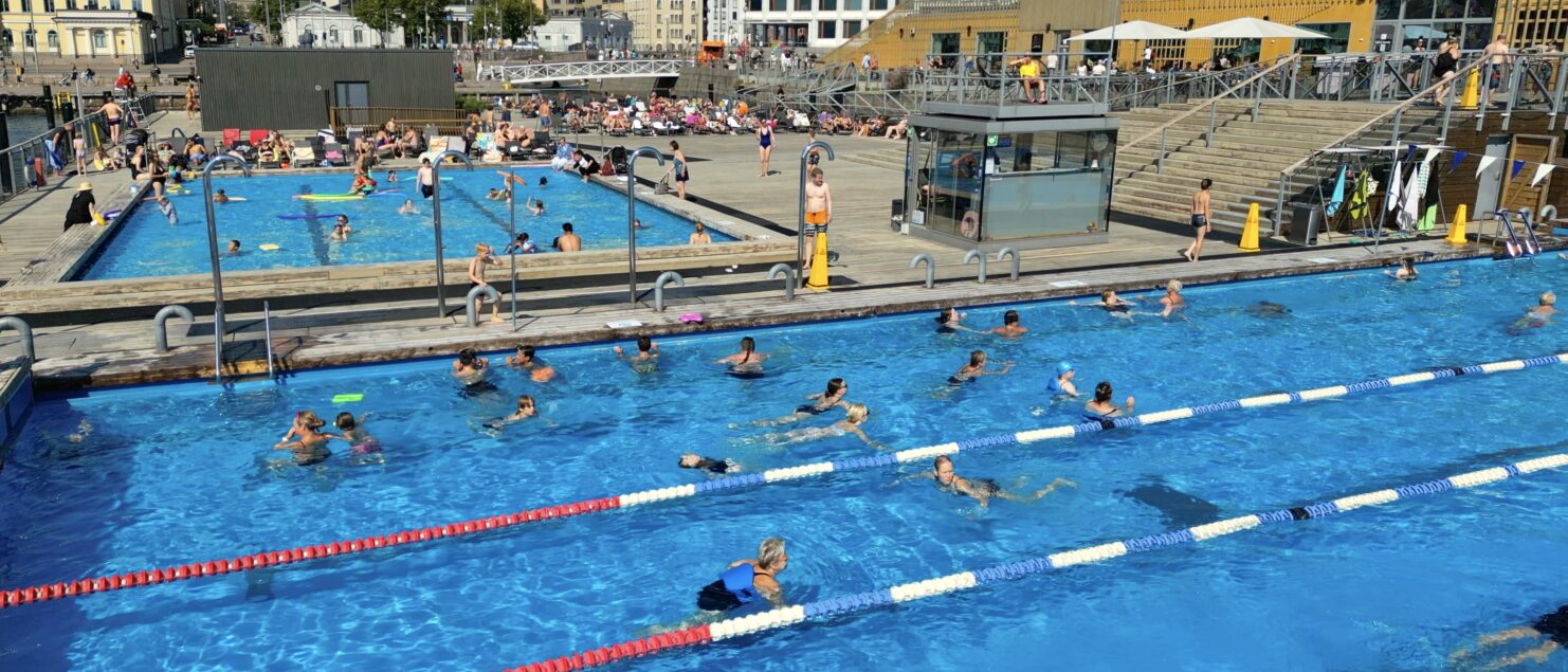 People swimming in outdoor swimming pools on a sunny summer day.