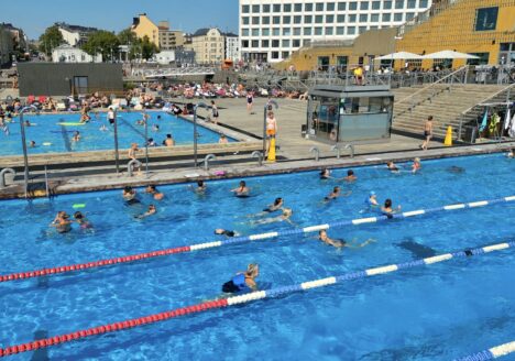 People swimming in outdoor swimming pools on a sunny summer day.