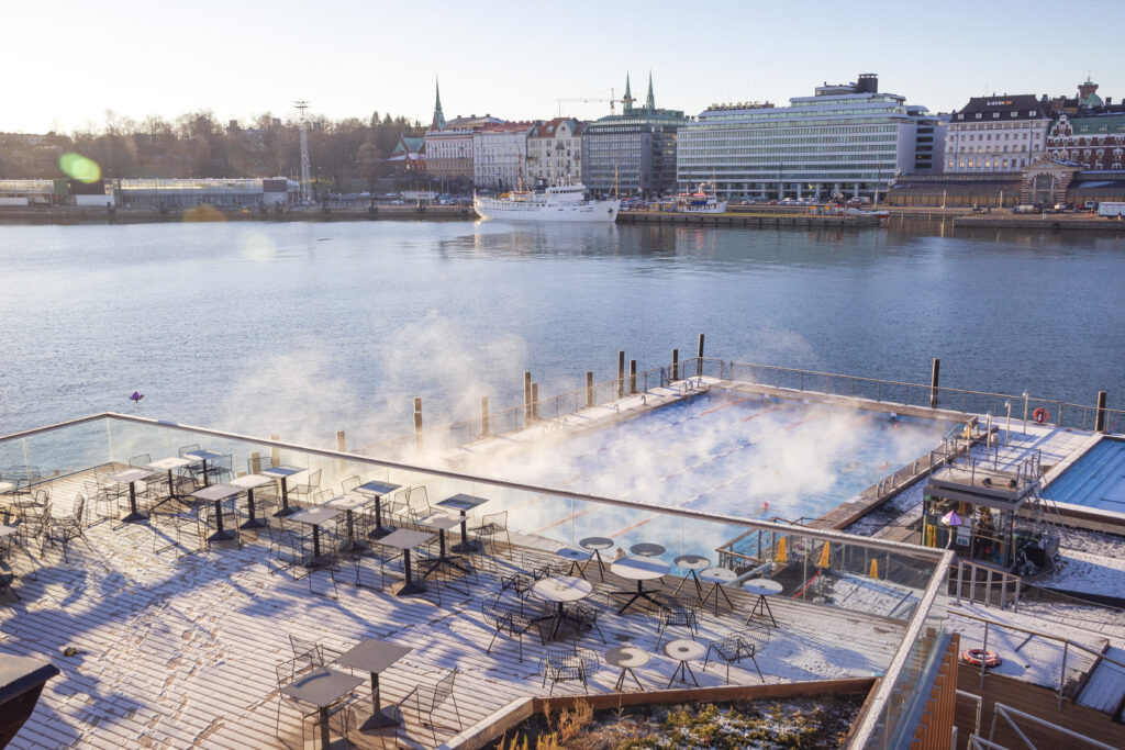 A floating swimming pool in Helsinki's old harbor in cold weather. The pool is covered in steam arising from the warm water.